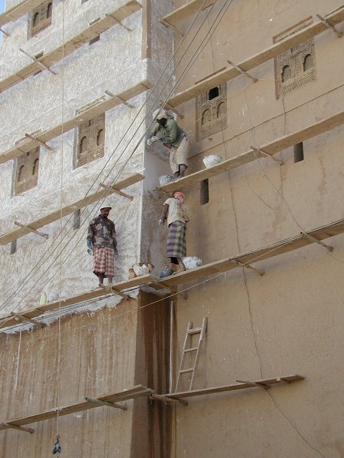 epa000445987 This photo taken on 25 May 2005 shows workers restoring a house in the historical city of Shibam, Hadhramout province (some 500 km from the Yemeni capital, Sana'a). At the end of December 1984, the United Nations Education, Scientific and Cultural Organization- UNESCO- issued a plea to the world to save another national treasure from disintegration: the mud-brick buildings "skyscrapers built in the 18th and 19th centuries" in historic Hadramout's Shibam in South Yemen. Two years earlier, UNESCO completed a study of the skyscrapers and added them and the Wadi Hadramout to UNESCO's World Heritage list. EPA/YAHYA ARHAB
