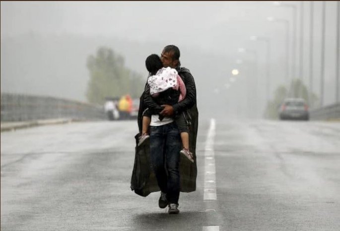 Πρόσφυγας κρατάει σφιχτά το παιδί του στη βροχή στα σύνορα Ελλάδας - Βόρειας Μακεδονίας. Η φωτογραφία βραβεύτηκε με Πούλιτζερ
